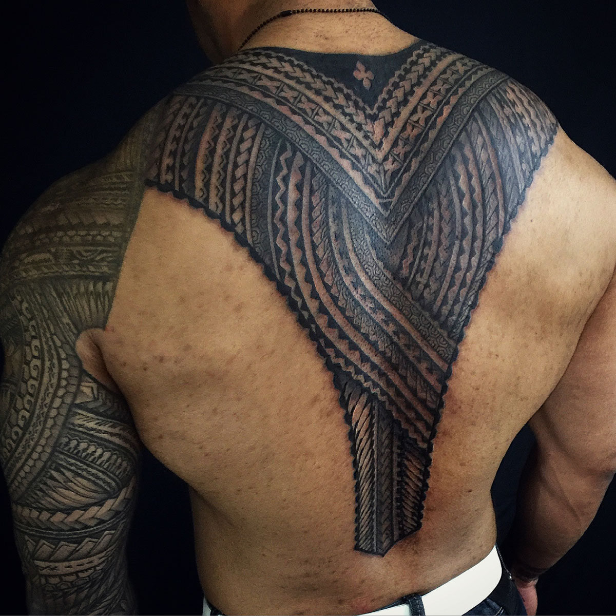 Large black and gray geometric tattoo across the upper back