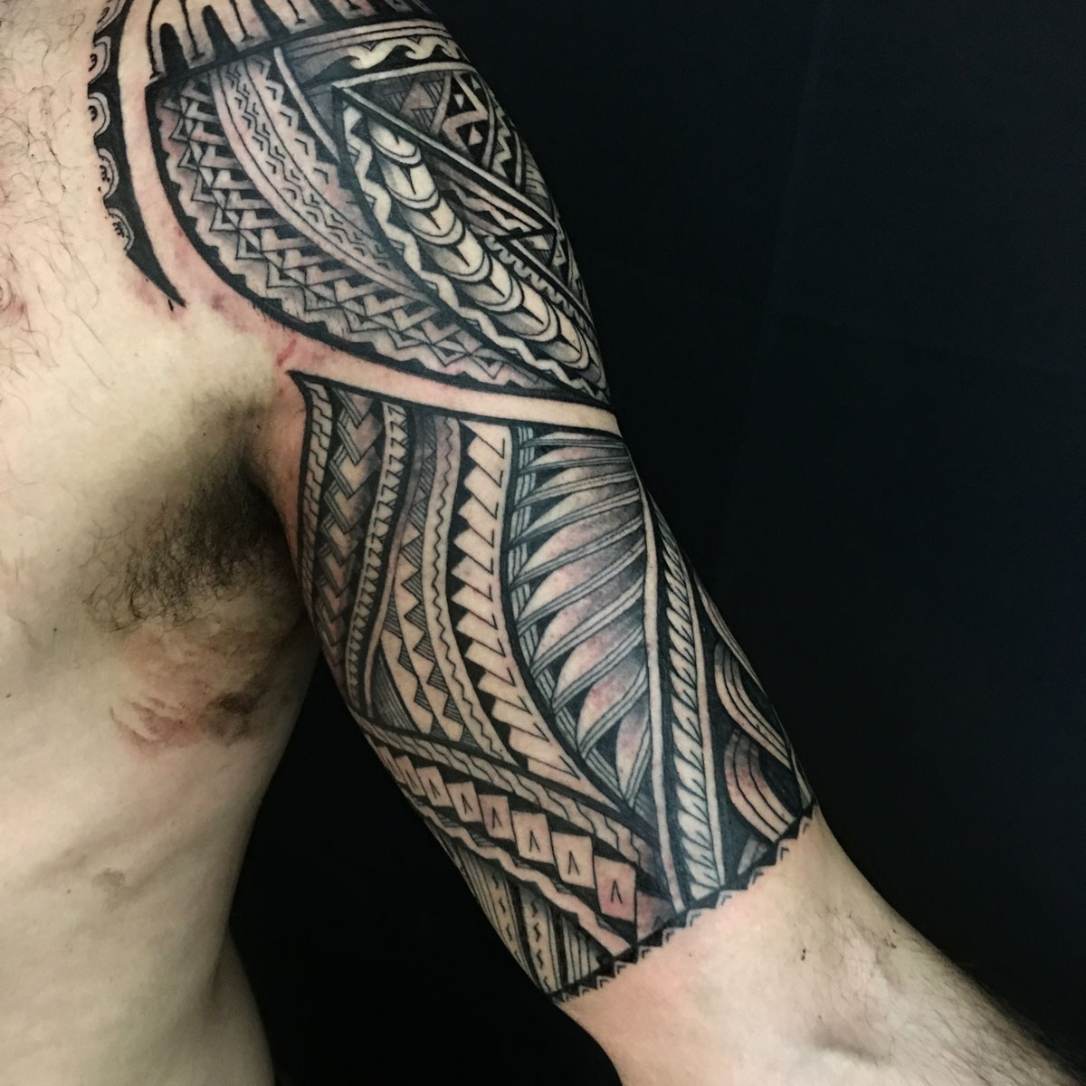Black and gray geometric tattoo spanning the shoulder and upper arm